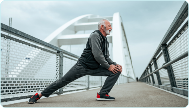 Older adult man stretching his legs on a pedestrian bridge during an outdoor workout.