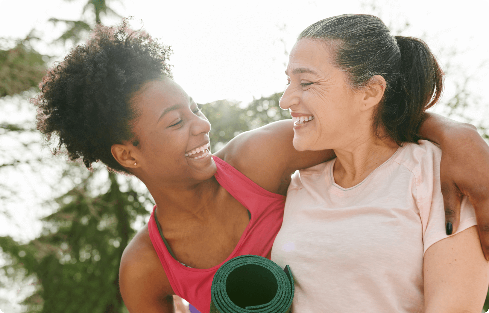 younger-woman-older-women-talking A younger woman and older woman are outside. The younger woman has her arm around the older woman and the two are talking and smiling at each other.