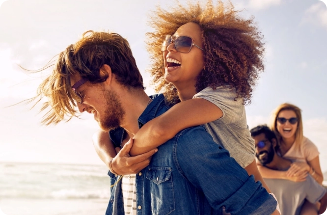 Woman hugging man from behind at the sea shore.