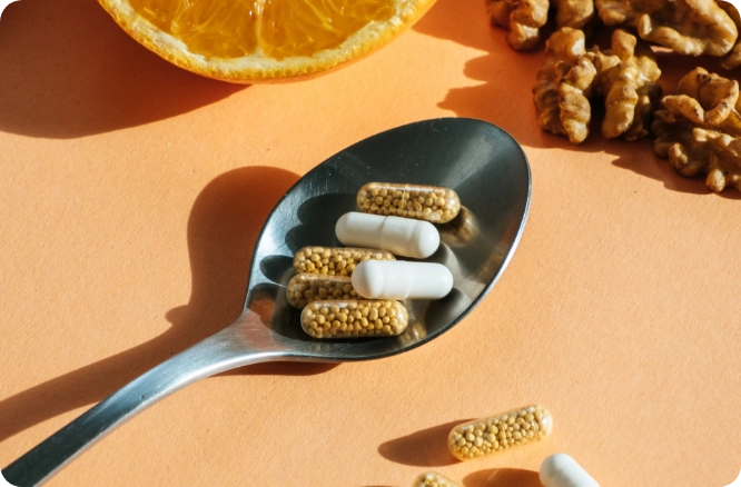 Spoon on table carrying nutritional supplement pills.