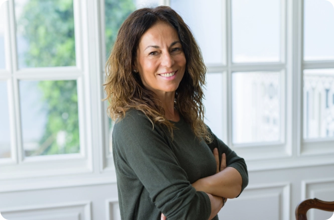 Woman posingand smiling in front of windows.