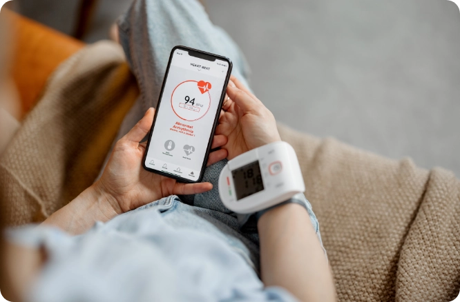 Woman using a blood pressure monitor and related app.