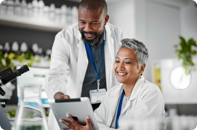 Man and woman in lab coats looking at an electronic tablet.