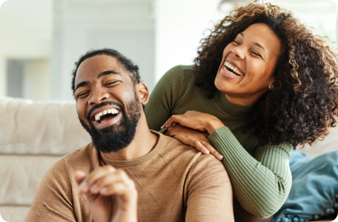 Man and woman laughing together in living room.