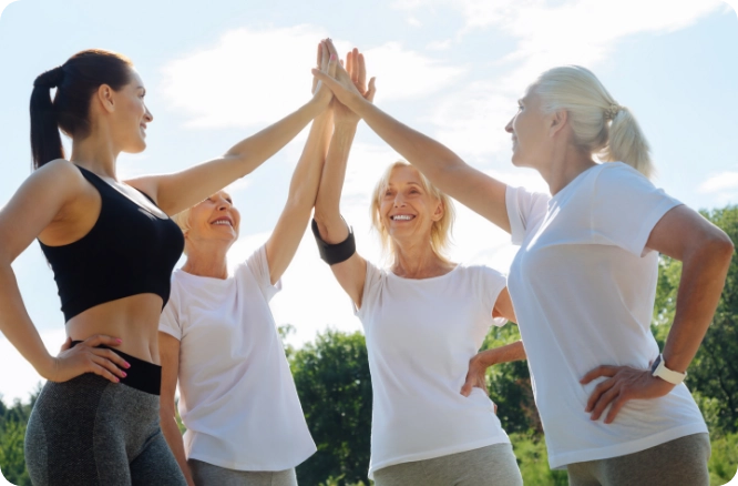Four adult female runners of various ages performing a high-five.