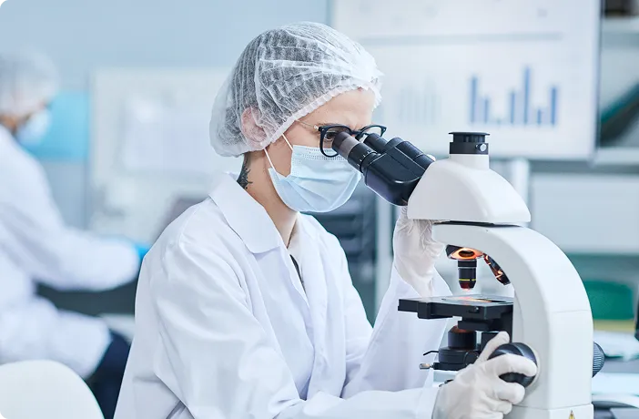 nutraceutical-ingredient-quality-control-lab-researcher-microscope Laboratory researcher examines a sample under a microscope, representing scientific testing and nutraceutical ingredient quality control.