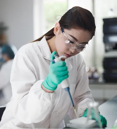 Laboratory researcher examines a sample under a microscope, representing scientific testing and nutraceutical ingredient quality control.