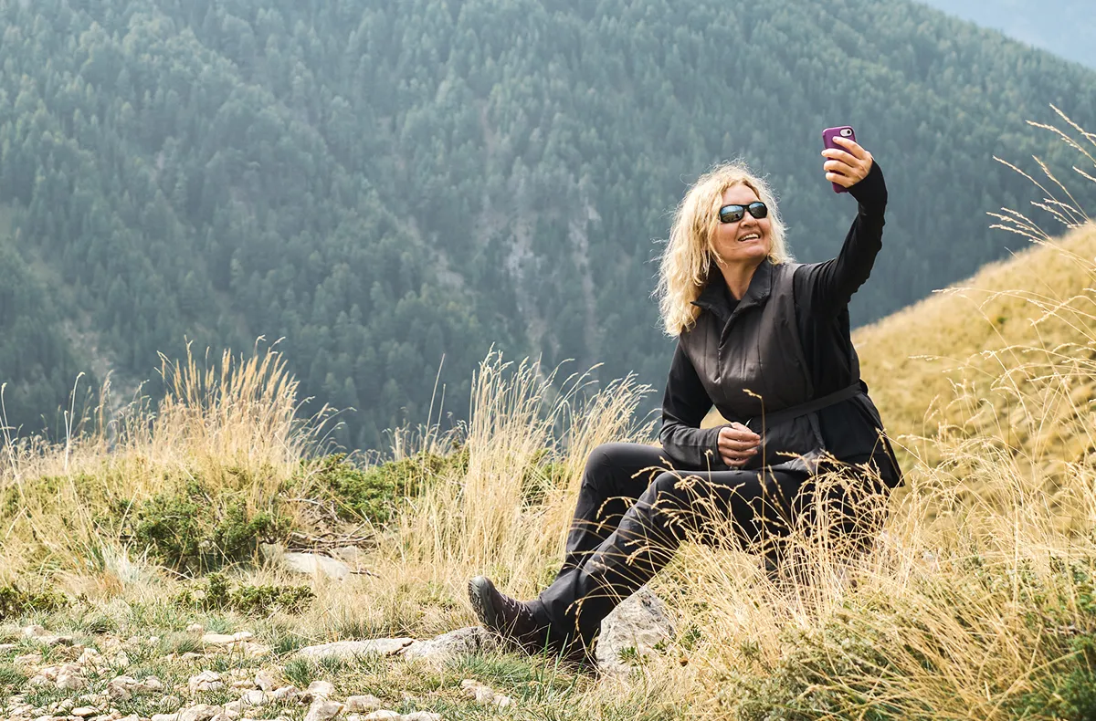 Woman in hiking gear resting on a high-altitude mountainside, illustrating how exertion and altitude shift antioxidant balance across the lifespan.
