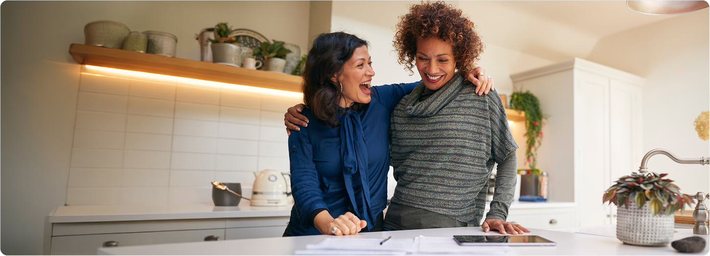 Two midlife women laughing in a kitchen, representing Kaneka Ubiquinol clinical evidence in women's mitochondrial health.